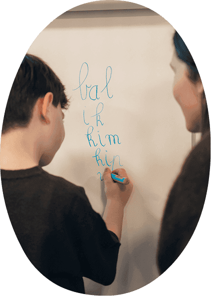 Kind schrijft woorden op een bord tijdens logopedie bij Praktijk VONK